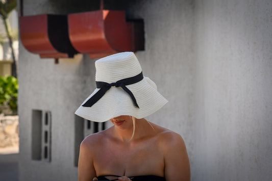 Woman wearing a large white sun hat outdoors.