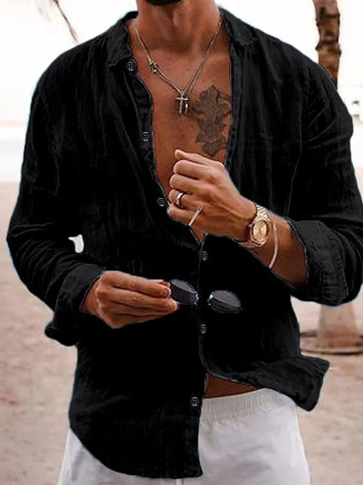 Man in a casual open black shirt with layered necklaces, styled with a relaxed vacation vibe—men’s tops for cruise and resort wear.