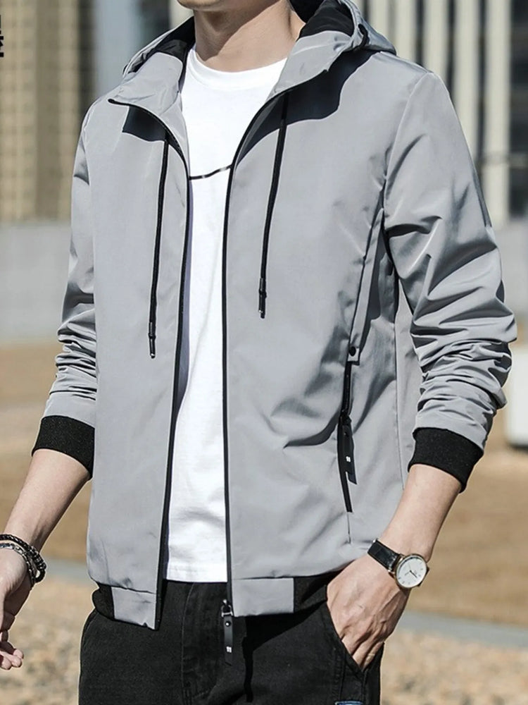Man wearing light gray zip-up jacket over white shirt, showcasing men’s outerwear for casual travel style.