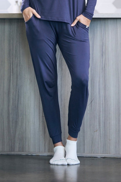 Person wearing a navy blue tracksuit with white socks against a gray wooden panel background