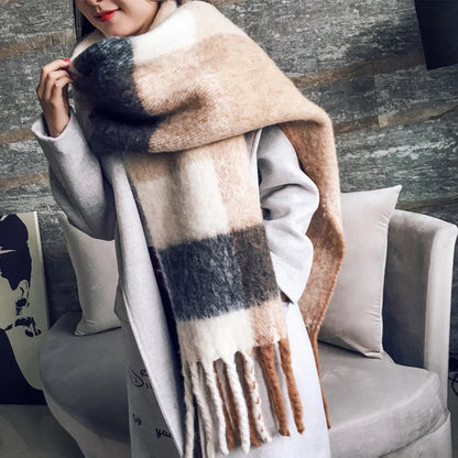 Person wearing a large plaid scarf in a cozy indoor setting