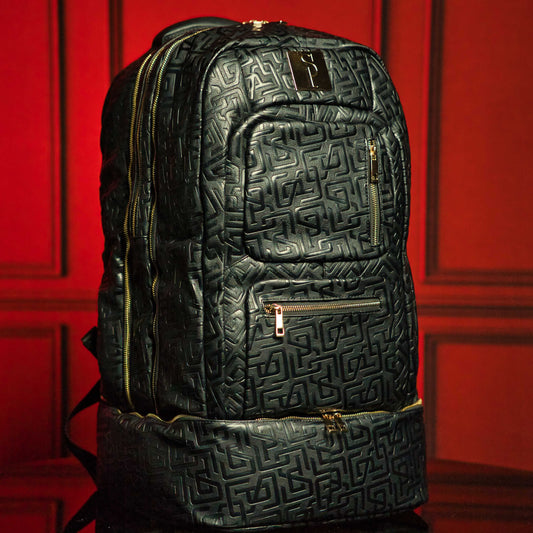 Black textured backpack with gold zippers on a red background