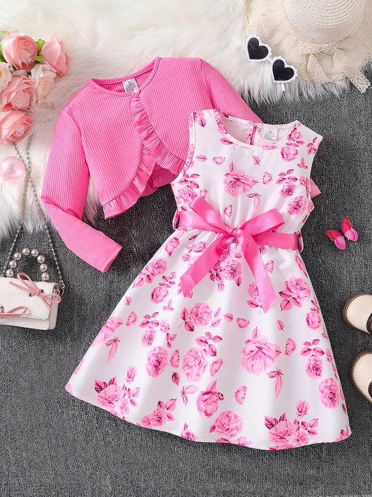 Pink floral dress with matching cardigan on a textured surface with decorative items.
