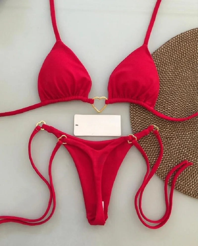 Red bikini set on a white surface with a brown textured mat in the background.