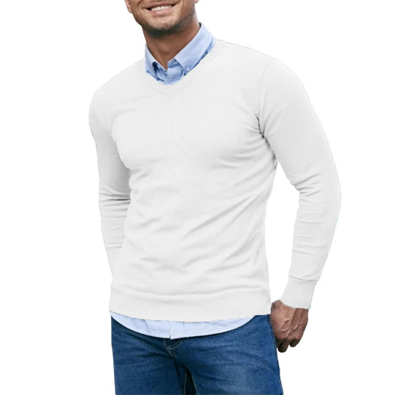 Man wearing a light gray sweater over a blue shirt with jeans on a white background