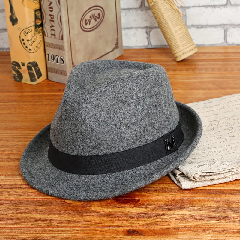Gray fedora hat with a black band on a wooden surface