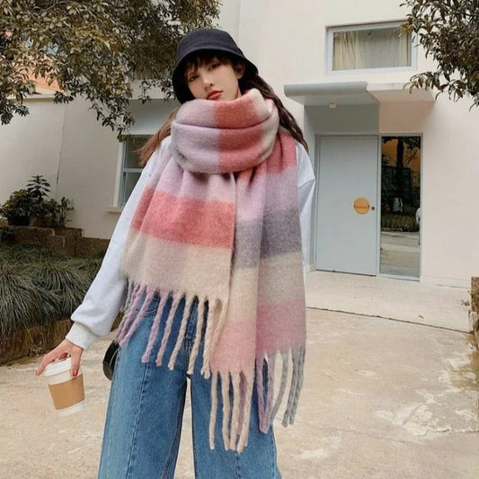 Person wearing a pink and beige plaid scarf outdoors.