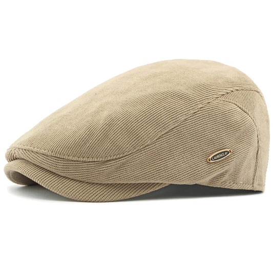 A light tan corduroy flat cap with a small oval brand patch on the side, photographed on a clean white background.