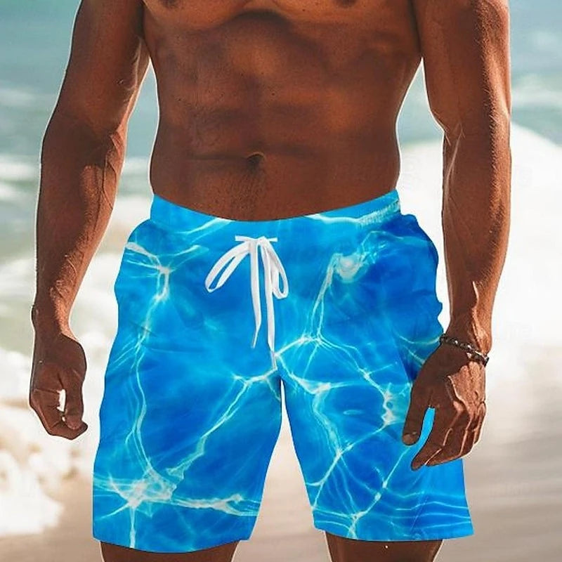 Person wearing blue swim shorts with a marble pattern on a beach.