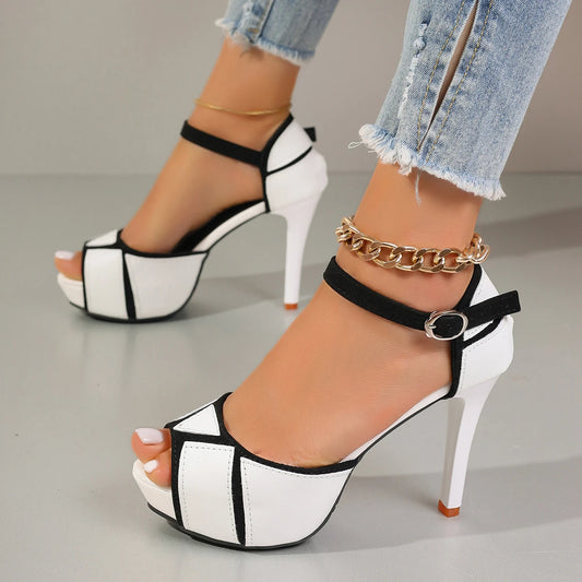 White and black platform high-heeled sandals worn with denim jeans on a neutral background