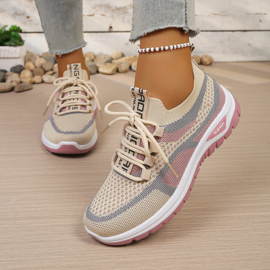 Beige and pink sneakers with white laces on a wooden floor.
