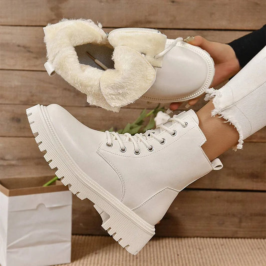 White winter boots with fluffy lining held by a hand against a wooden background