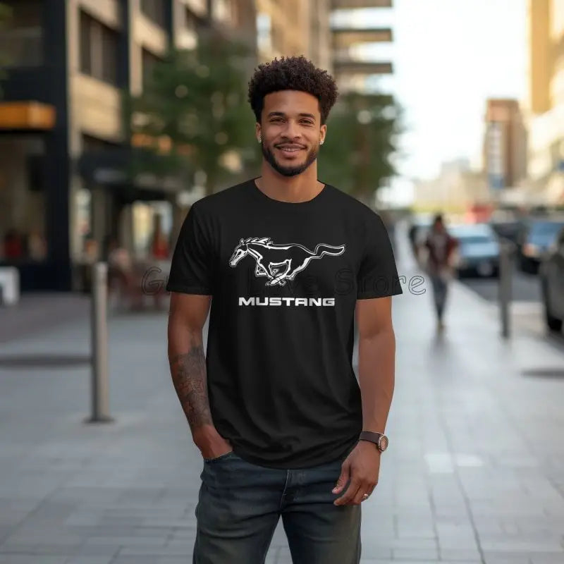 Man wearing a black t-shirt with Mustang logo on a city street