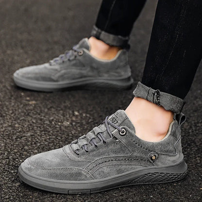 Gray suede sneakers worn on a dark surface