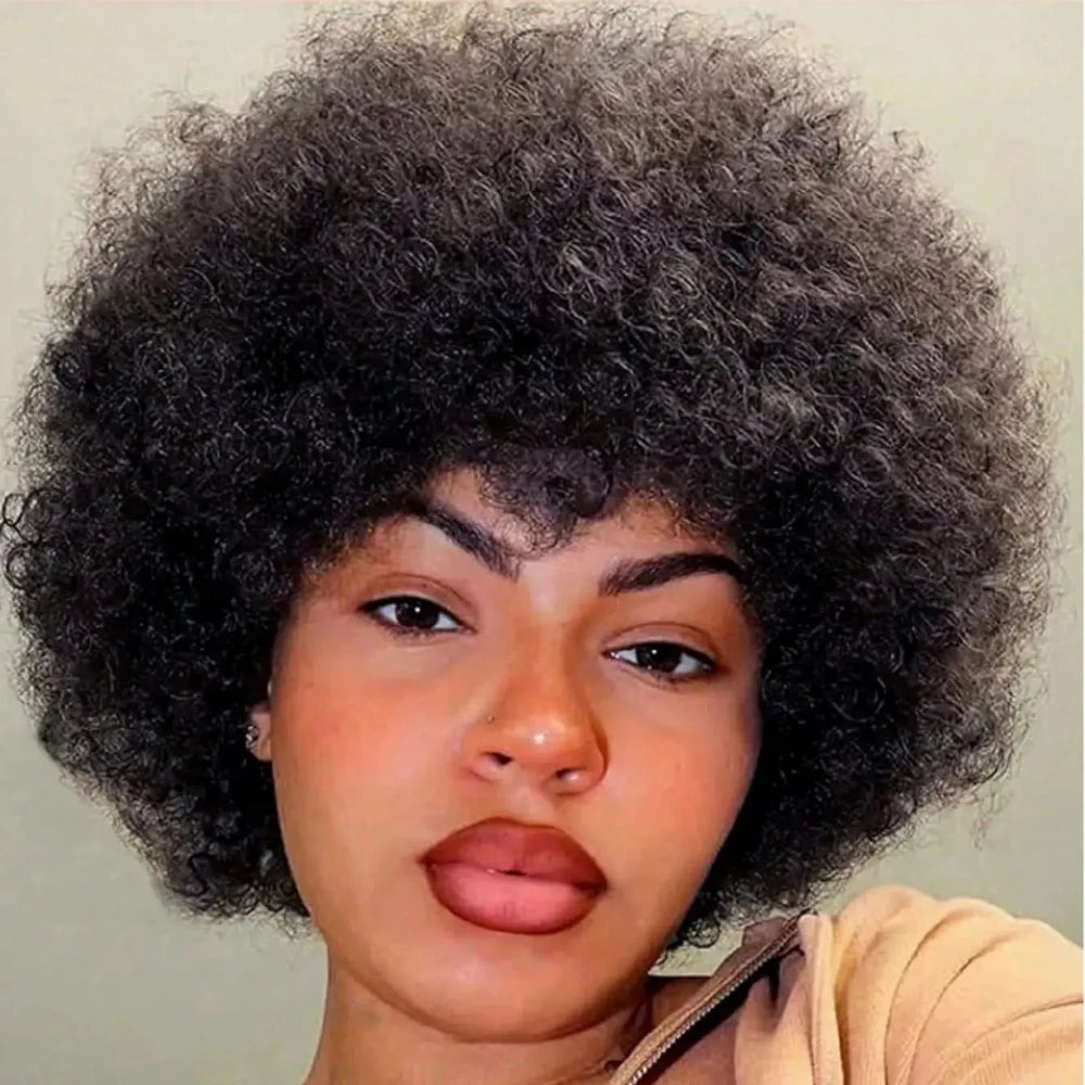 Person with large, bushy eyebrows and afro hair against a plain background