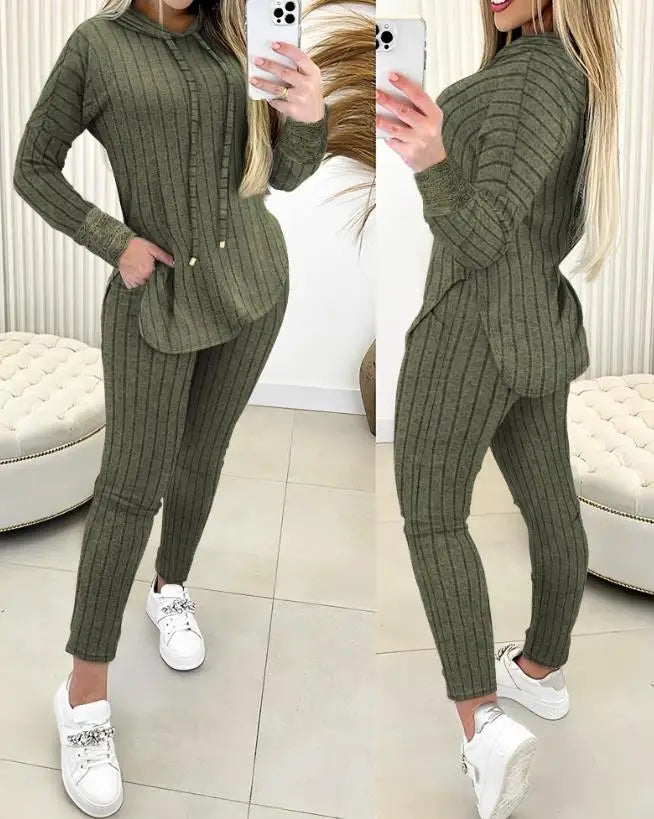 Person wearing a green ribbed sweater and pants set, standing in a room with white furniture.