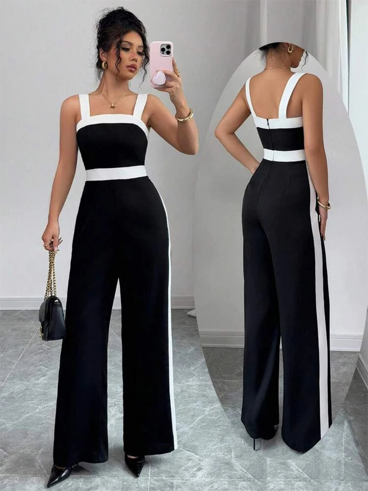 Woman wearing a black and white jumpsuit taking a mirror selfie.