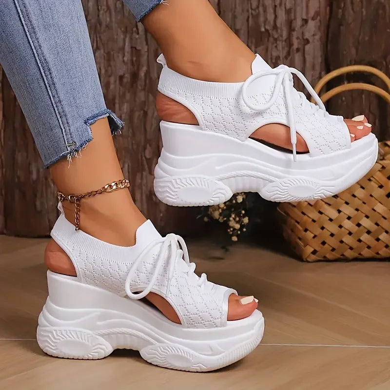 White platform sandals worn with light blue jeans on a wooden floor.
