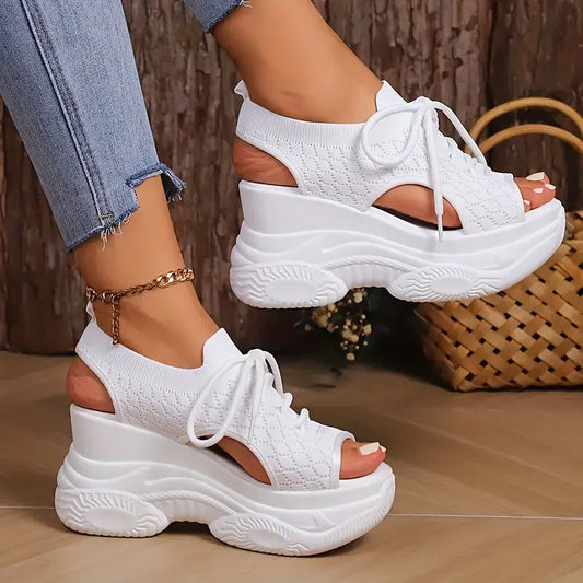 White platform sandals worn with light blue jeans on a wooden floor.