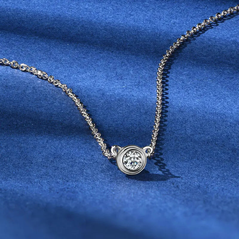 “Sterling silver, gold, and rose gold moissanite pendant necklaces displayed on blue fabric background”