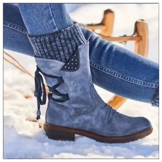Blue winter boots with lace-up design worn with jeans on a snowy background