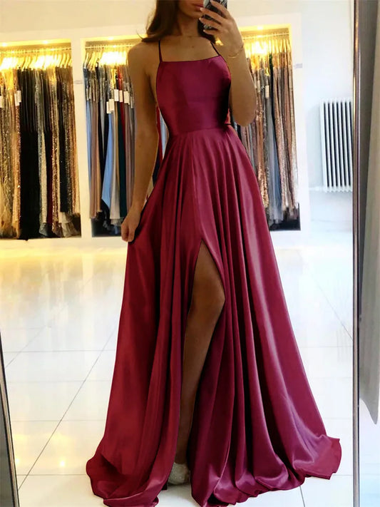 Woman wearing a burgundy evening gown with a slit, standing in front of a mirror.
