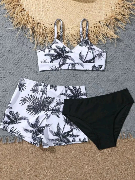 Black and white palm leaf bikini set on a textured surface with a straw hat.