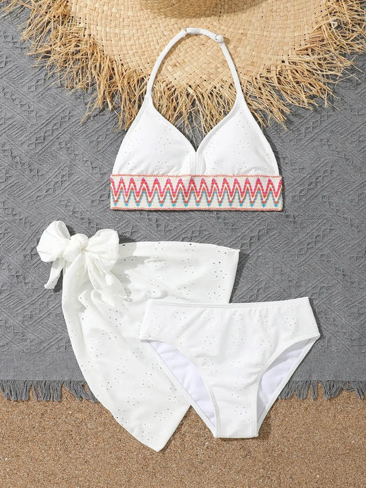 White bikini set with red and pink embroidery on a textured surface
