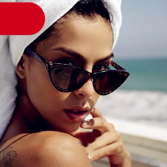 Woman wearing sunglasses and a towel on her head by the beach